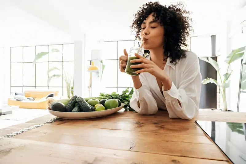Una mujer tomando un zumo verde