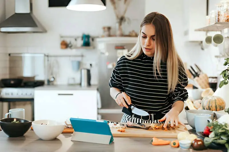 Una mujer haciendo una receta y consultando los datos de la misma en una tablet.