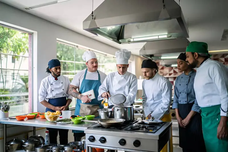 Un grupo de cocineros observando la técnica de cocción que utiliza el chef