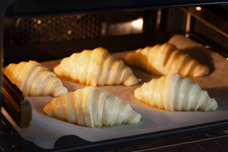Cinco croissants crudos recién metidos en el horno